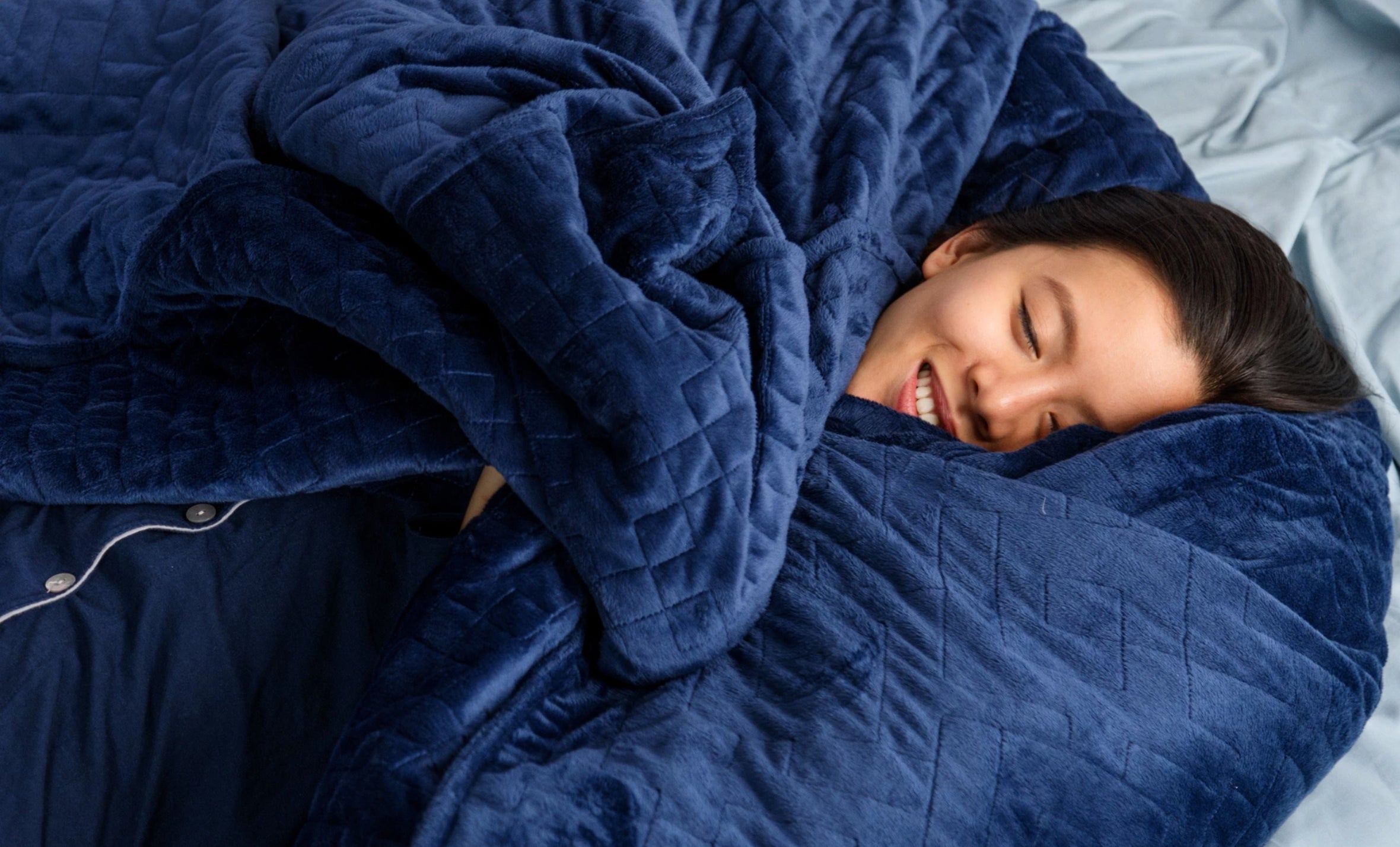 Woman nestled into a dark blue gravity blanket