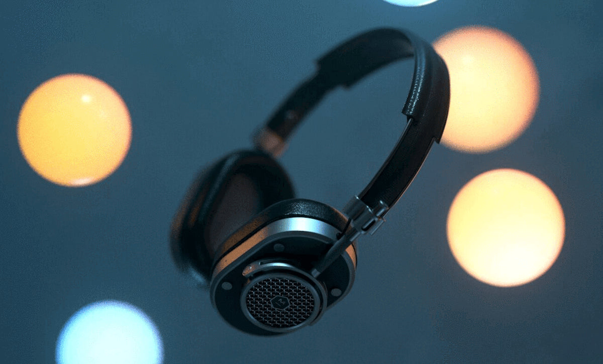 Master and Dynamic wireless headphones in black floating against a bokeh blue background