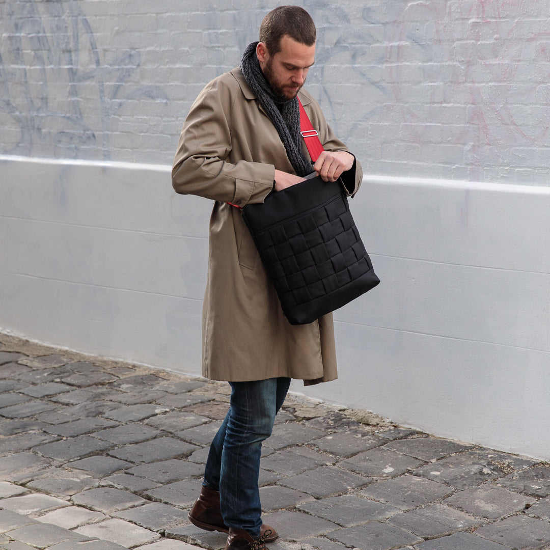 Matt Thomson is the maker behind Mattt, is standing with one of his black shoulder bags. 