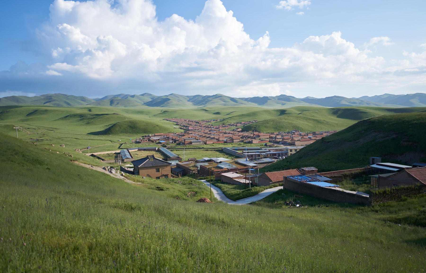 Landscape of lush green grass surrounding the village of Ritoma and it’s terra cotta colored roofs. 