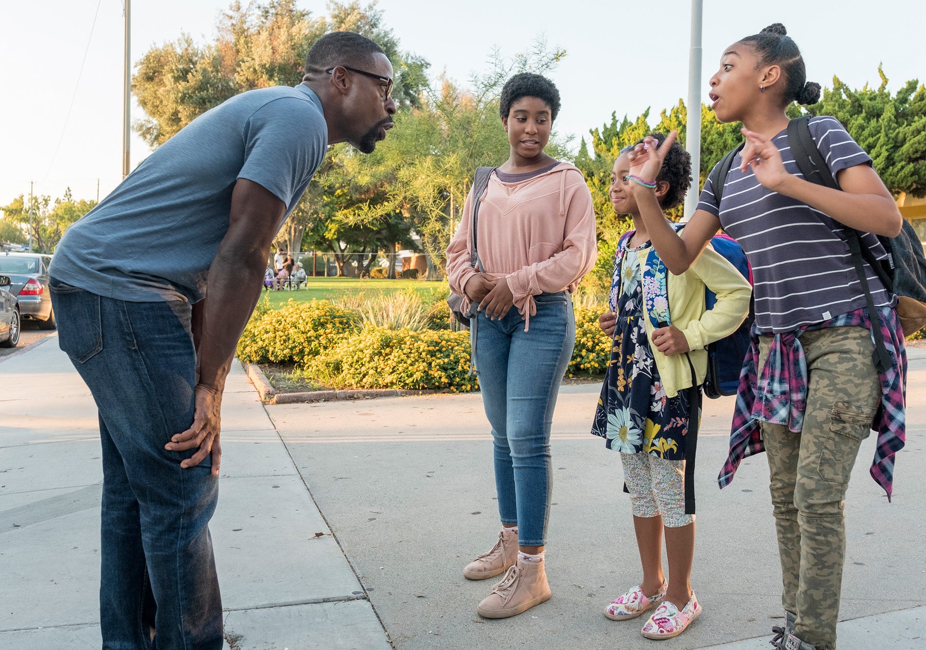 Randall Pearson (Sterling K. Brown) crouches to speak to his daughters in an outdoor scene in an episode of This Is Us.