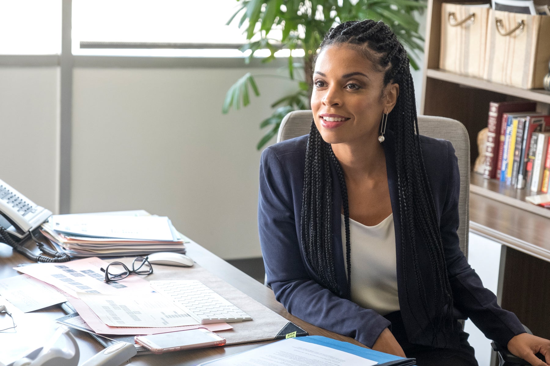 Beth Pearson (Susan Kelechi Watson) sits at an office desk covered in papers, smiling off camera in an episode of This Is Us.