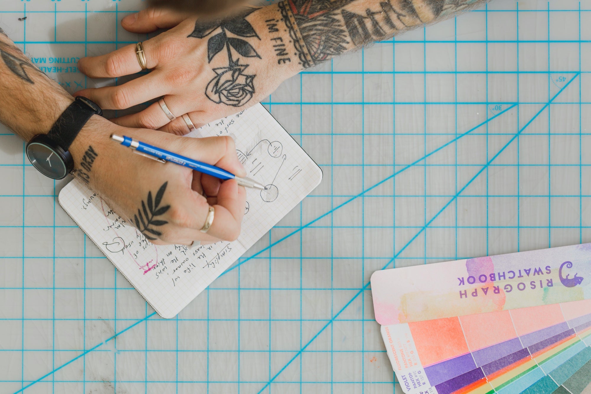 Mãos tatuadas escrevendo em um notebook