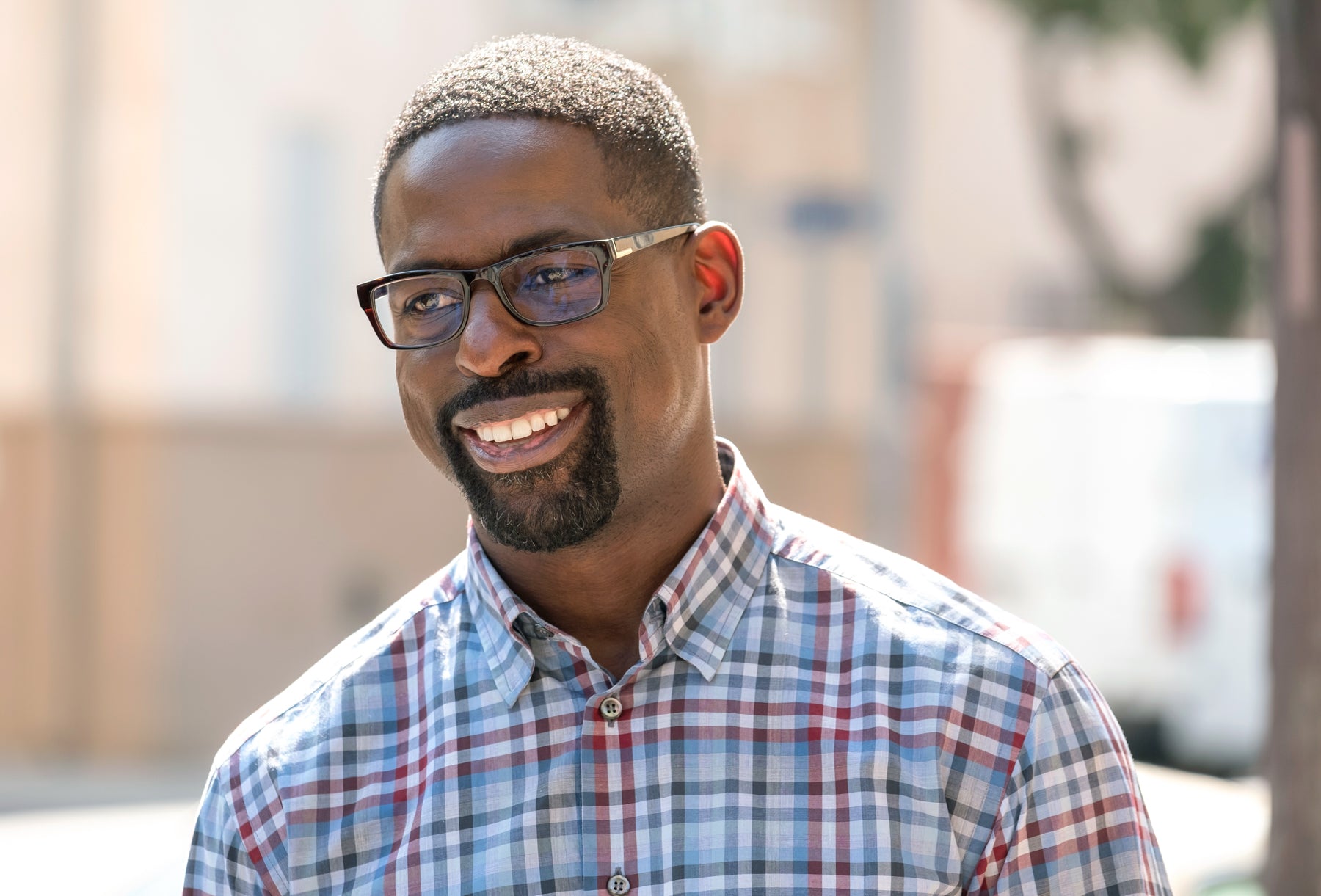 Randall Pearson (Sterling K. Brown) smiles off camera in an outdoor scene in an episode of This Is Us.