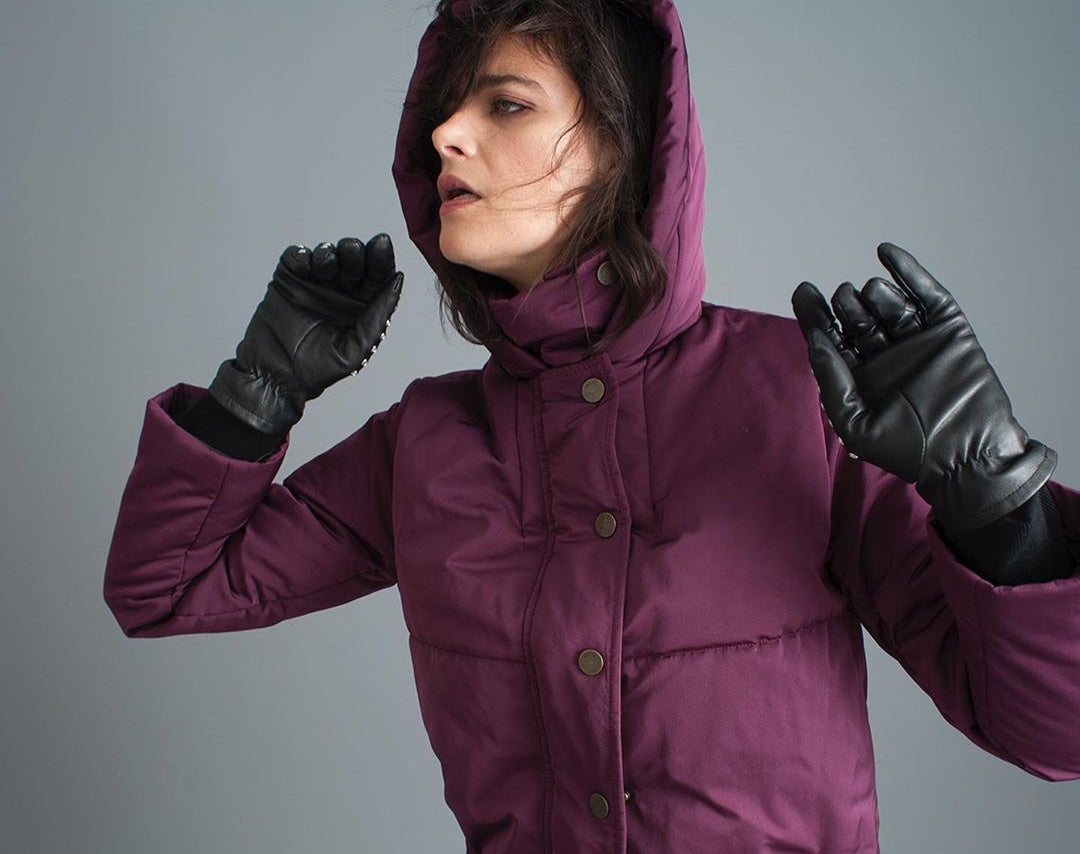 Woman wearing black gloves and an eggplant-coloured jacket with a hood by Vaute