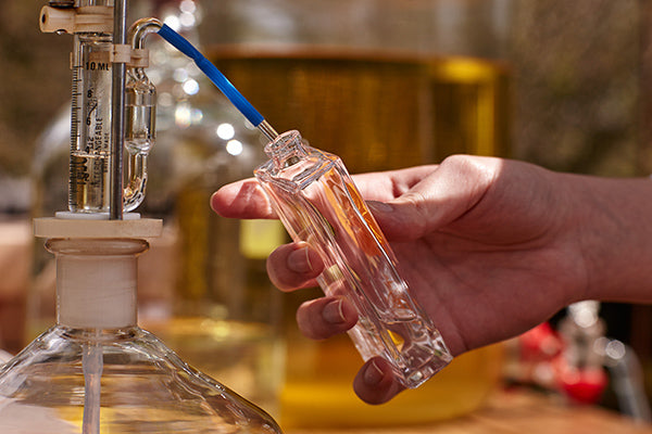 Glass perfume bottle being filled
