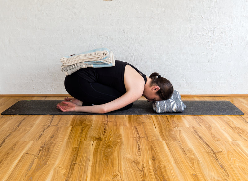 Balasana - Rest a folded blanket over the sacrum to encourage the back to melt toward the floor.