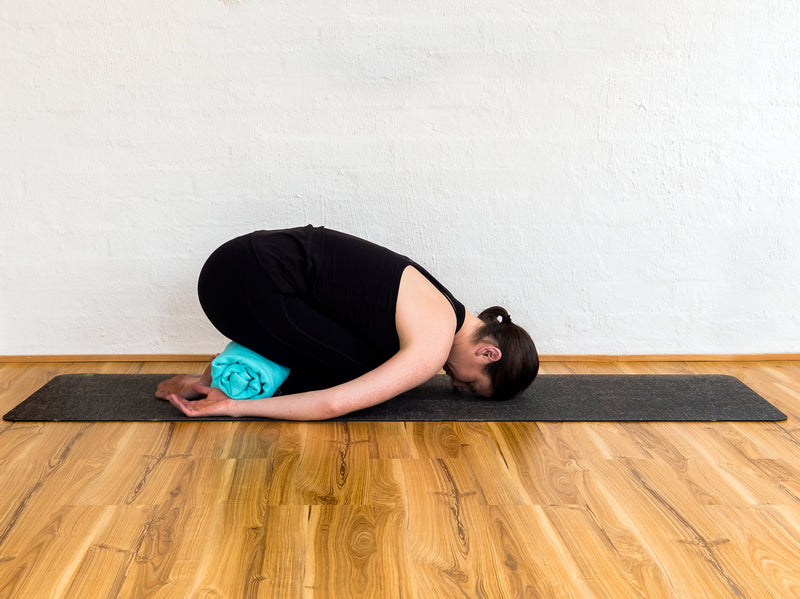 Balasana Pose using rolled yoga blanket