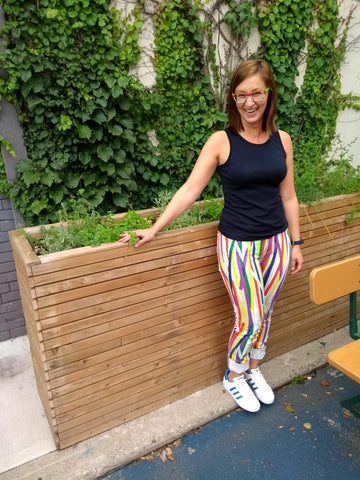 Sarah laughing in front of a flower box in colourful pants