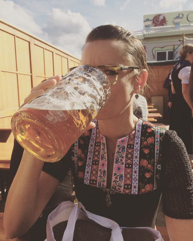 Eine Frau trinkt eine Maß Bier am Oktoberfest, prost.