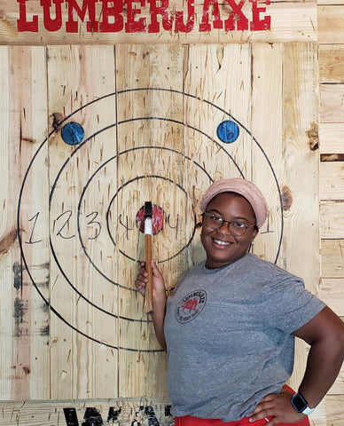 woman proudly displays axe on target