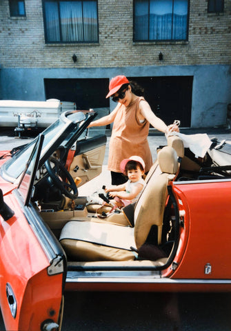 Pregnant mom and toddler daughter in red sports car