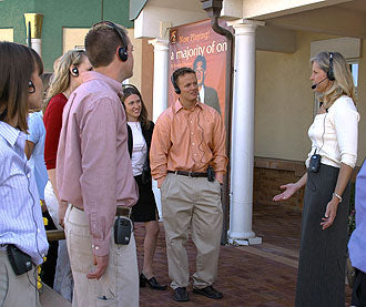 The speaker in white wears a portable tour-guide system (portable transmitter and headset microphone) as she addresses her listeners.
