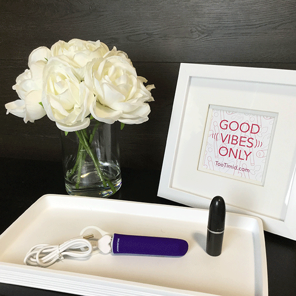 Purple Vibrator Shown On Nightstand Next To Lipstick Tube For Size Comparison