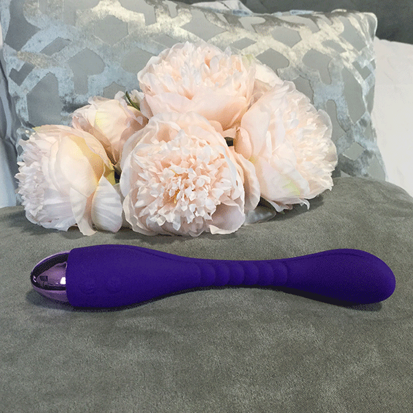 Flexible G Spot Vibrator Shown Laid On Bed Next To Bouquet Of Pink Flowers