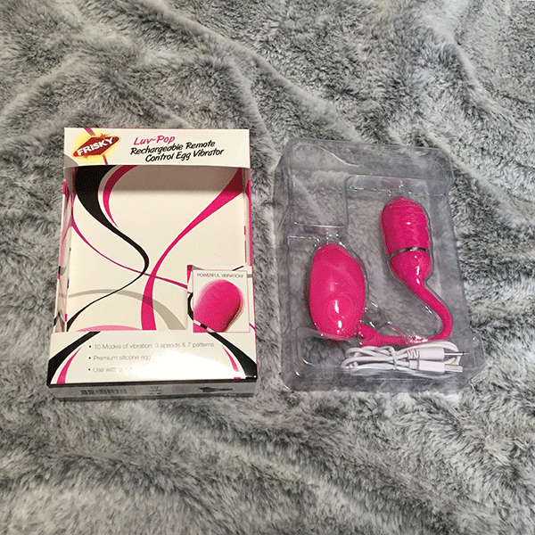 Pink Rechargeable Egg Vibrator Shown On Bed In Original Box Packaging With Charger