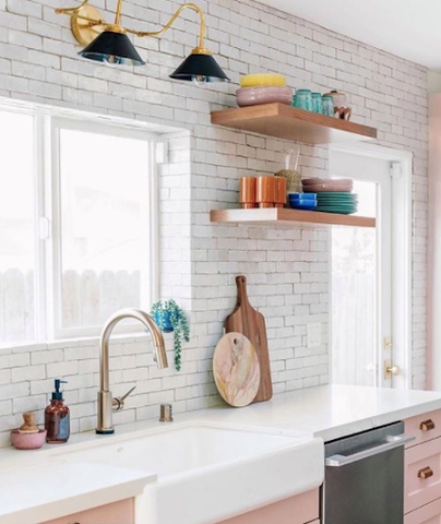 white and pink kitchen with gold wall lighting