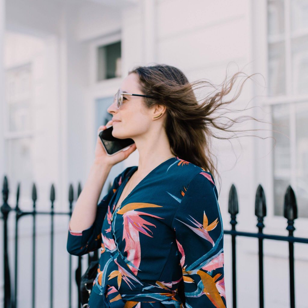 Jody Shield on the phone wearing floral clothing with wind blowing hair