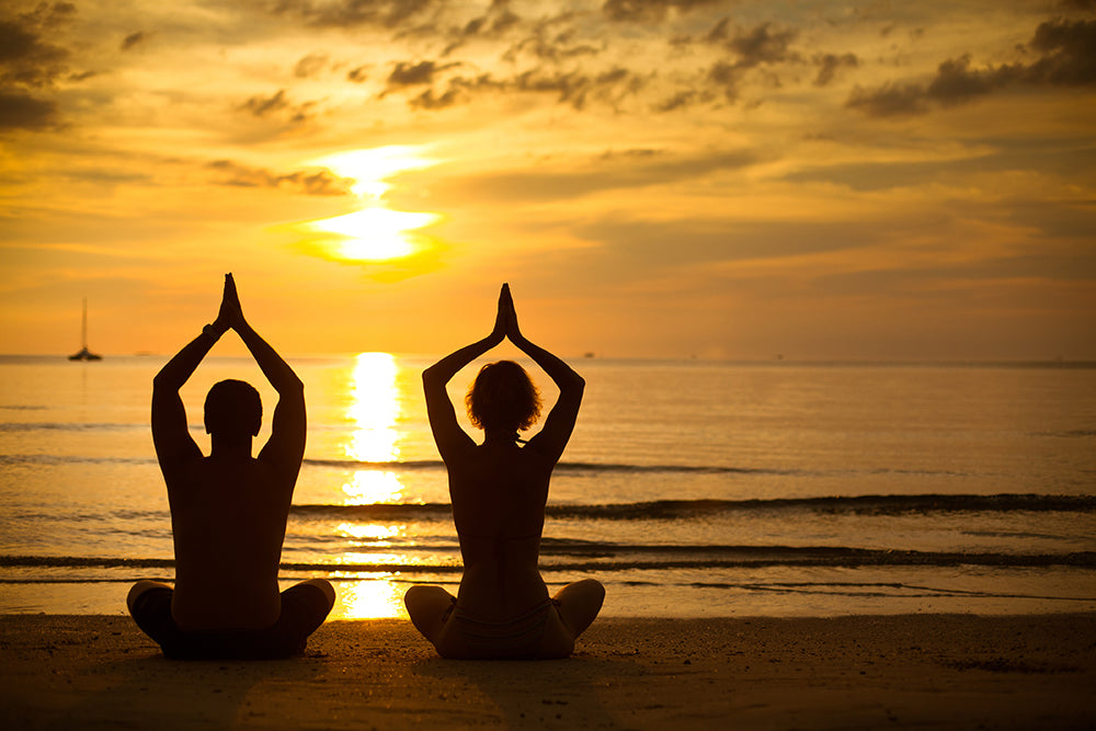 two people performing Yoga in sunset on Goa beach