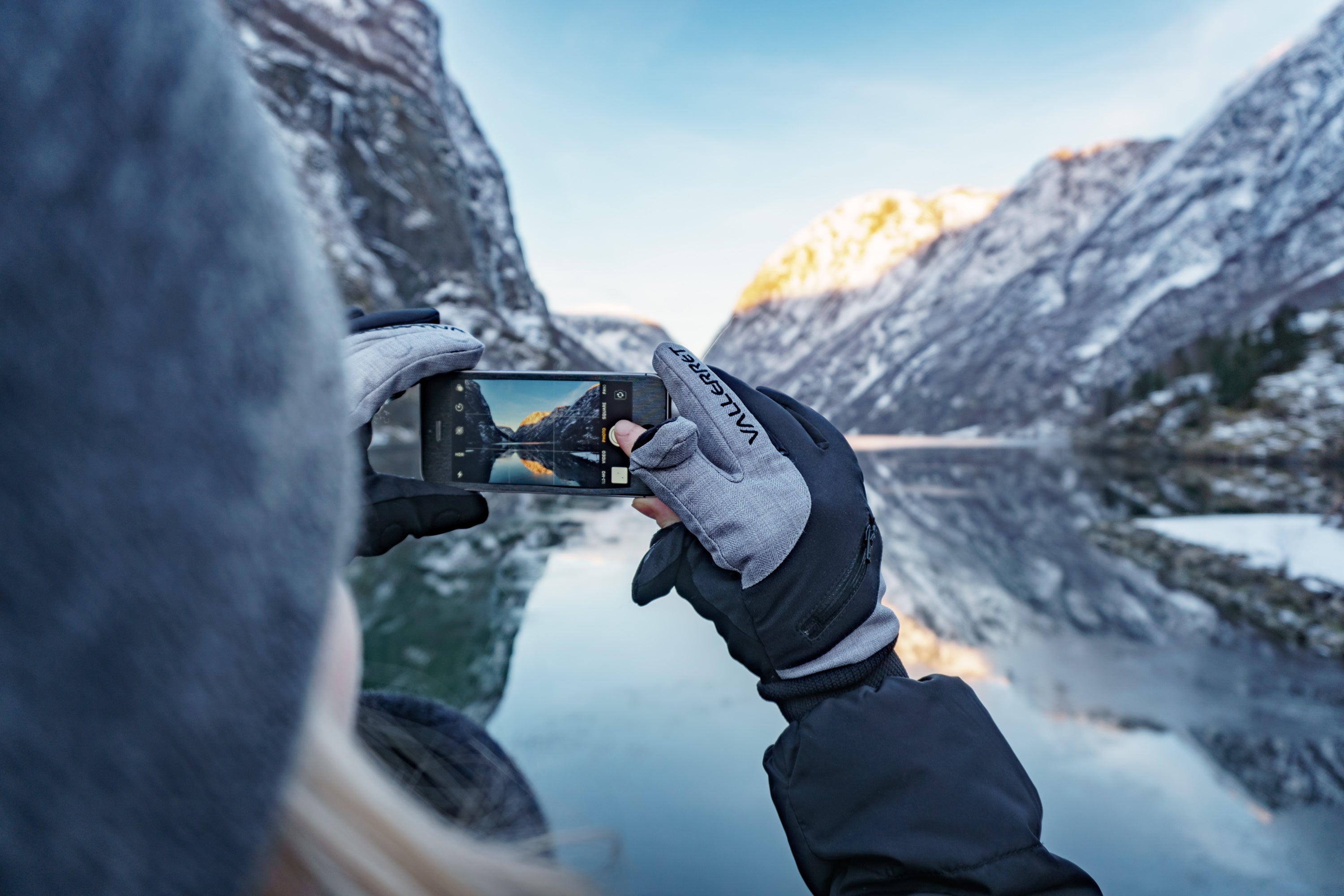 woman taking a photo on her phone of a mountain