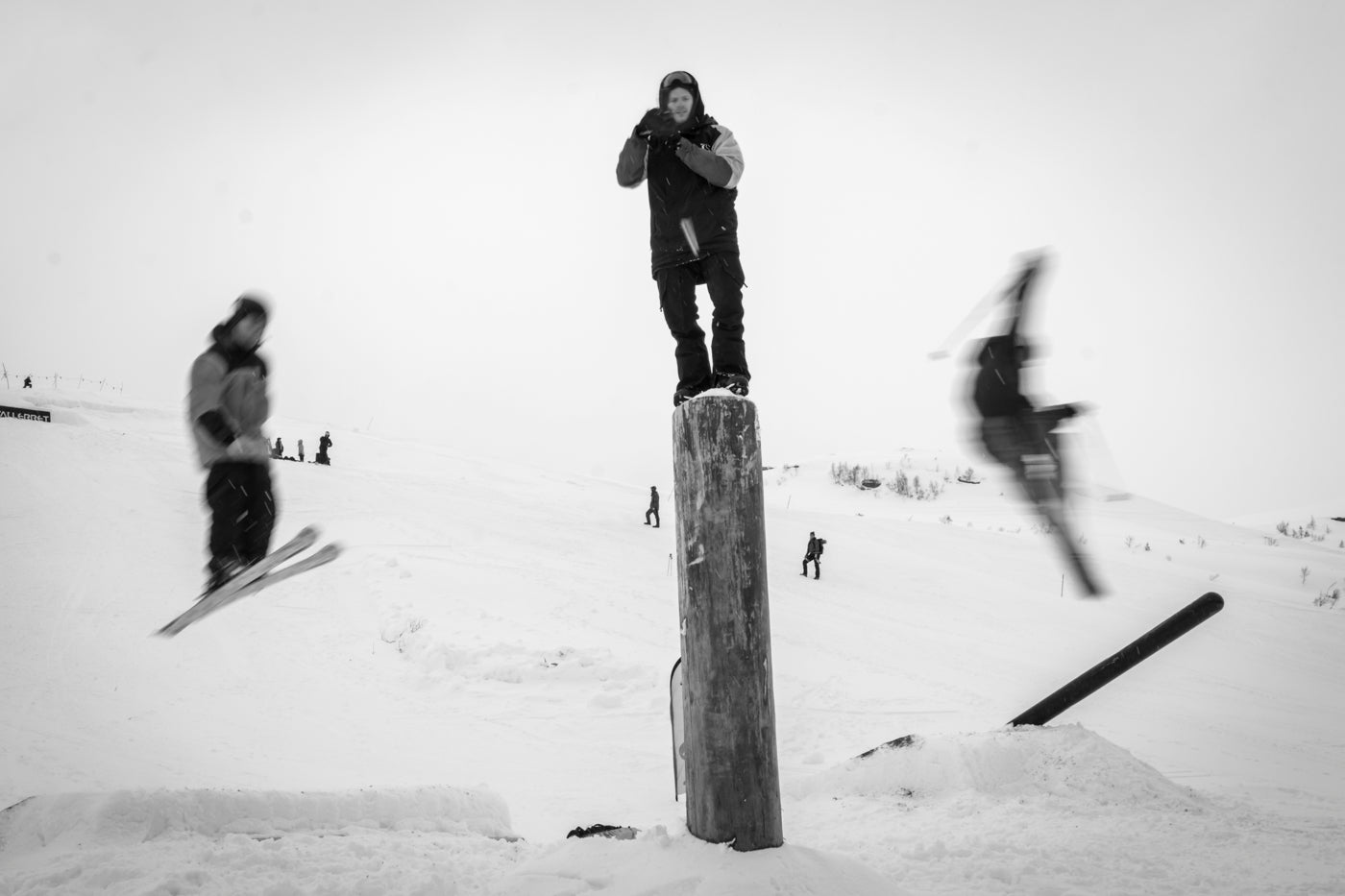 photographer on a post with skiers in the background