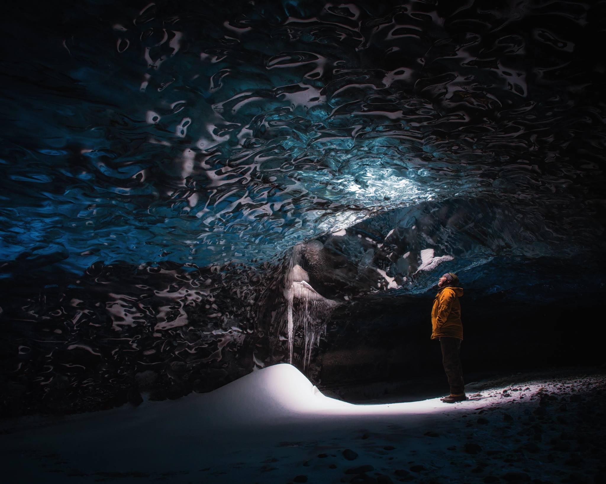 man standing in an ice cave looking up