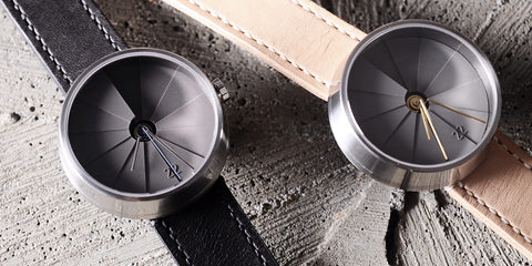 A duo of 22 Design watches laid on a concrete background