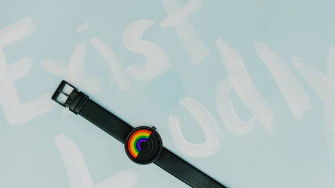 Pride Rainbow Watch on Light Blue Background with "Exist Loudly" in white text