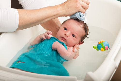 Little newborn baby having a bath