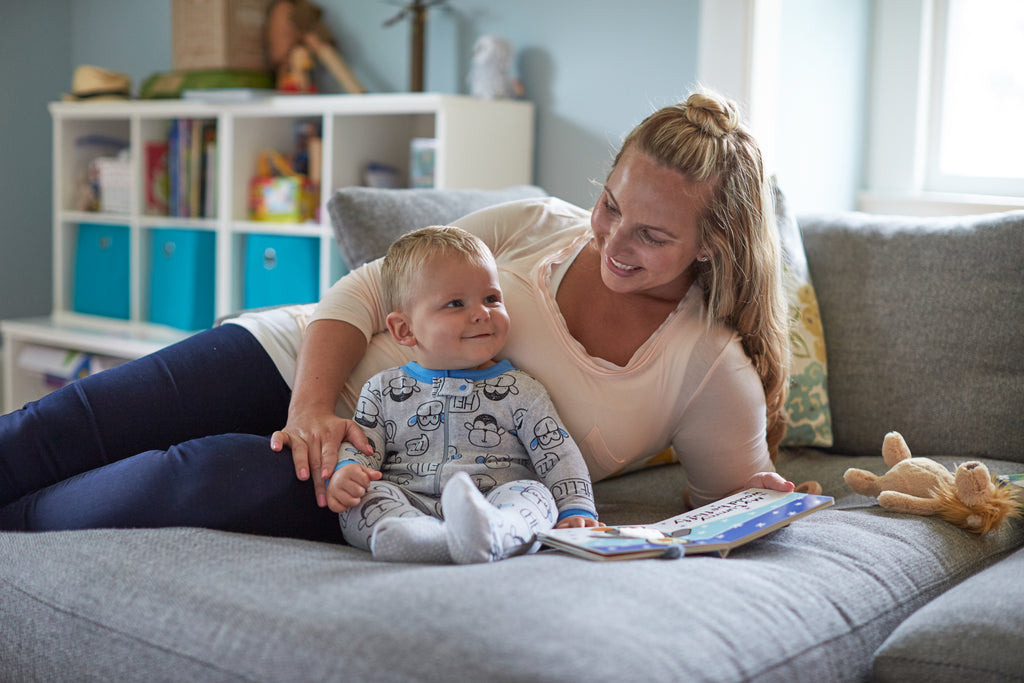 mom and baby boy relax on couch with picture book