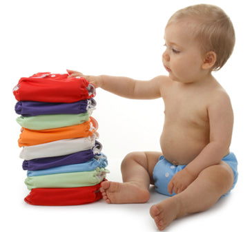 infant next to stack of cloth diapers