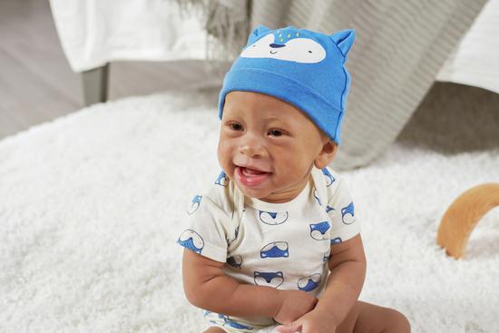 baby wearing animal bodysuit with blue hat