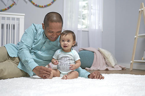An endearing scene of a man and a baby enjoying quality time while playing on a clean white rug.