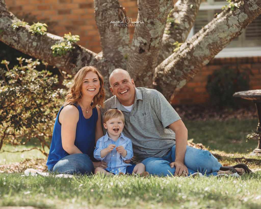 man, woman and boy pose outside in front of tree for picture