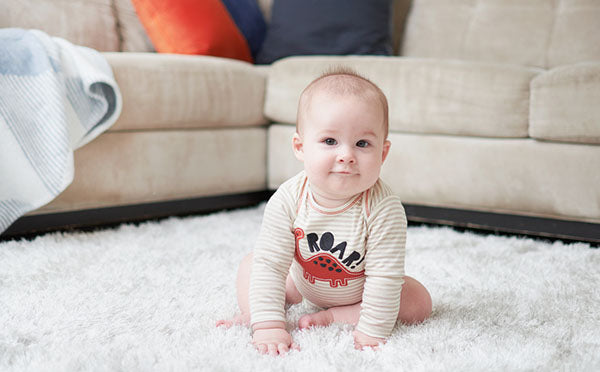 infant sitting on plush rug