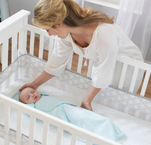 mom placing baby in crib