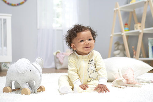 A cute baby sitting on a white rug, playing with an adorable elephant toy. Pure innocence and joy captured in one delightful image!