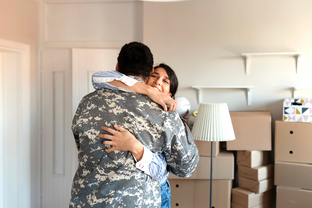 military moving day partners hug surrounded by cardboard boxes