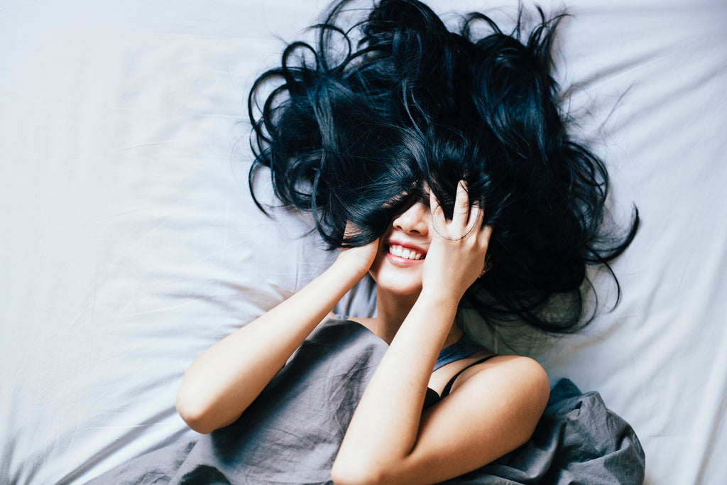 woman laughing on bed with messy hair