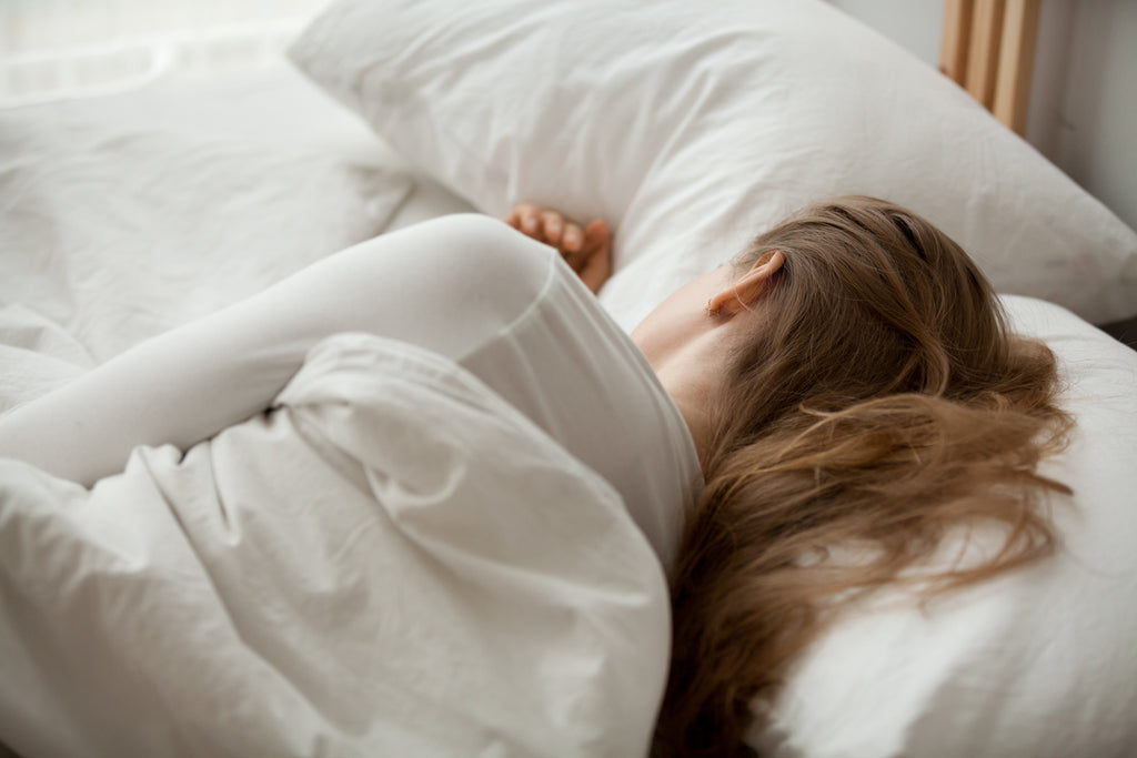 young female sleeping in bed next to empty space for spouse