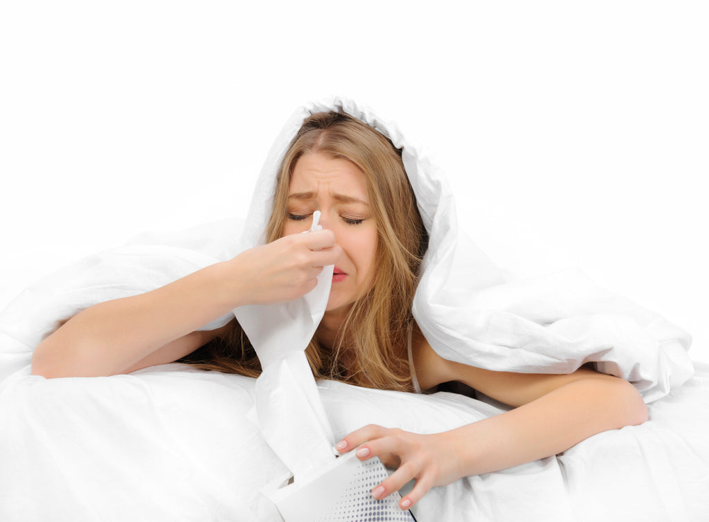 young woman blowing nose in bed