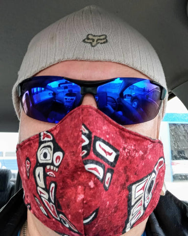 man with sunglasses and hat wearing a red non-medical face mask with west-coast Indigenous designs