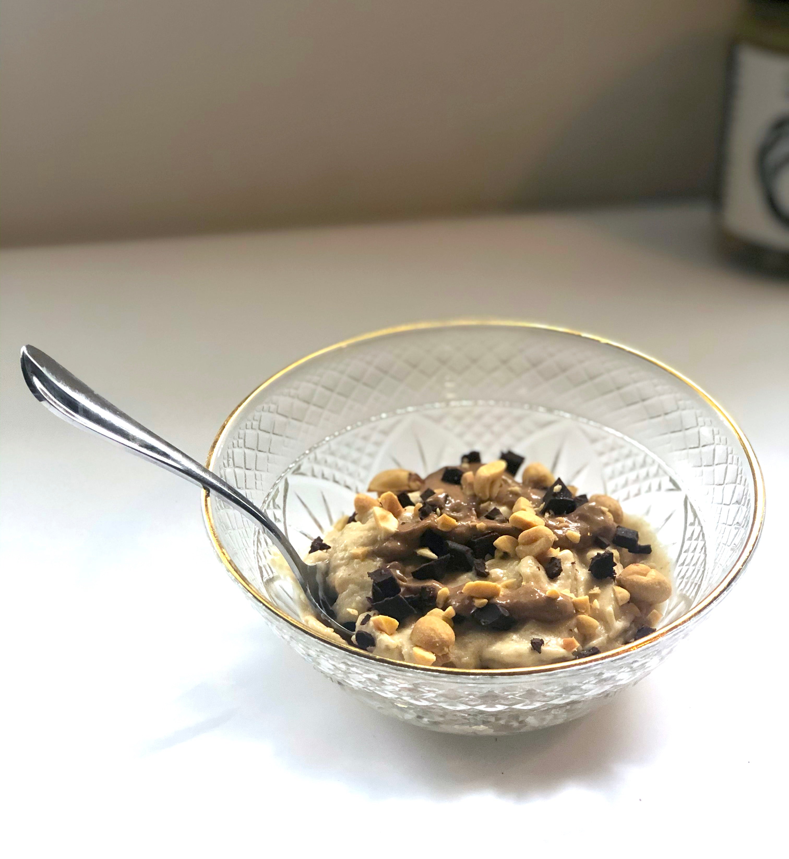 A bowl of Banana Natural Peanut Butter Nice Cream topped with chocolate natural peanut butter, peanuts and chocolate chips!