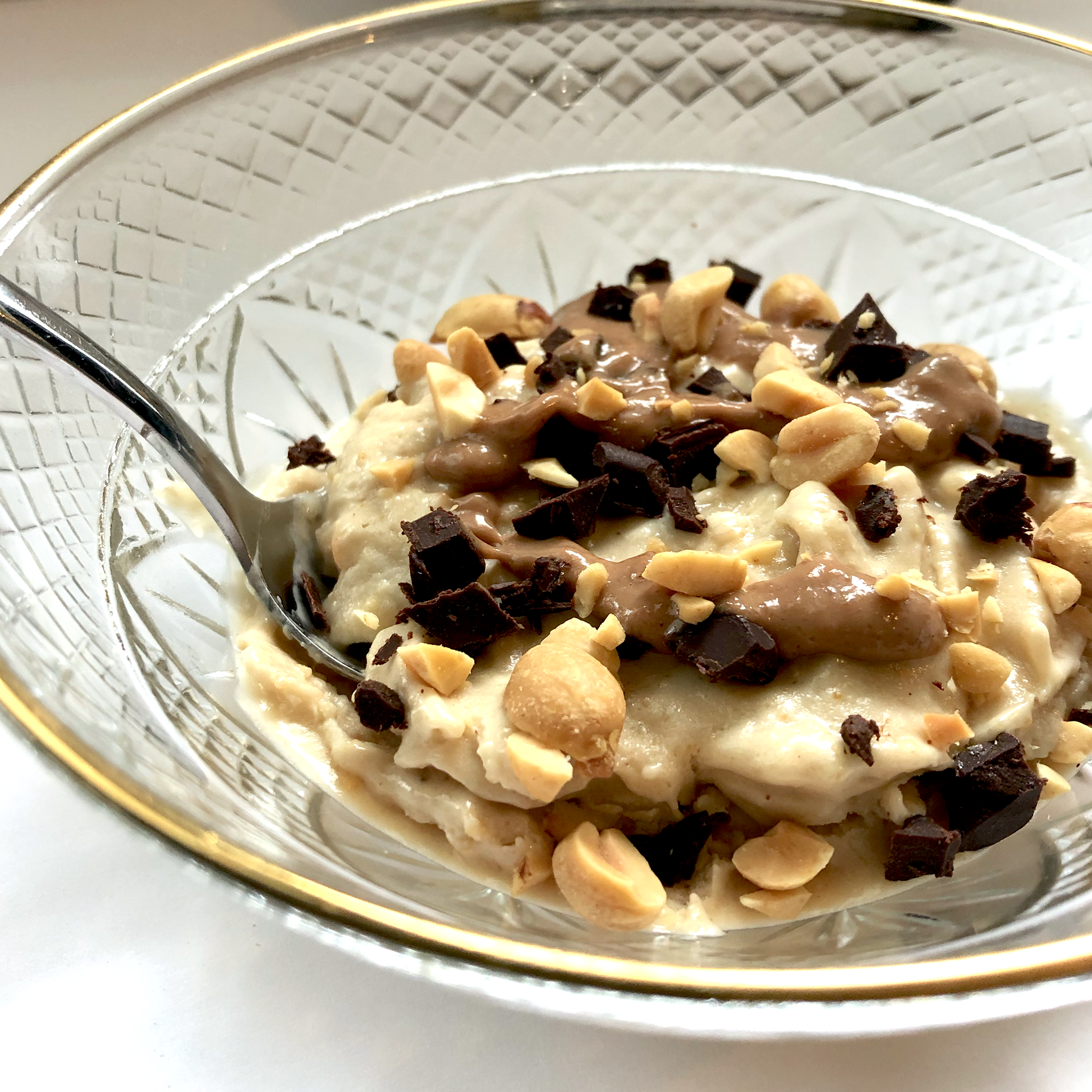 A bowl of Banana Natural Peanut Butter Nice Cream topped with chocolate natural peanut butter, peanuts and chocolate chips!