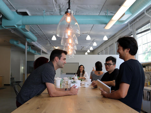 WAYB Lead Designer Kurtis Sakai at the WAYB kitchen table under turquoise ducts