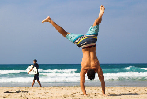the image shows a man doing a cartwheel on a beach