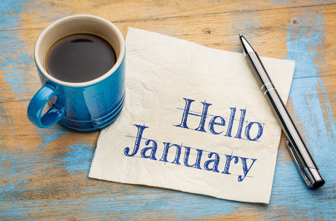 the image shows the words 'hello january' on a bit of paper next to a coffee cup