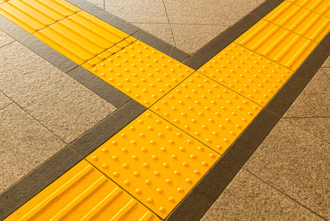 Close up of bright yellow Tenji Block surrounded by pavement
