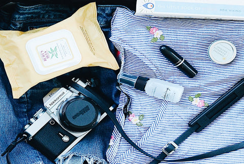 A close up of the content in an open suitcase – a shirt, camera, wet wipes, a book and some denim jeans