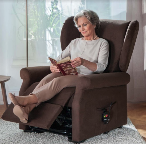 A lady sitting in an armchair reading a book